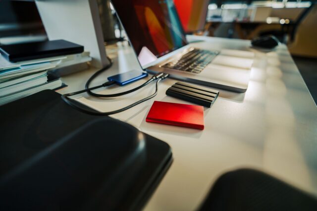 Disc extern așezat pe un birou, lângă un laptop, pentru copii de rezervă